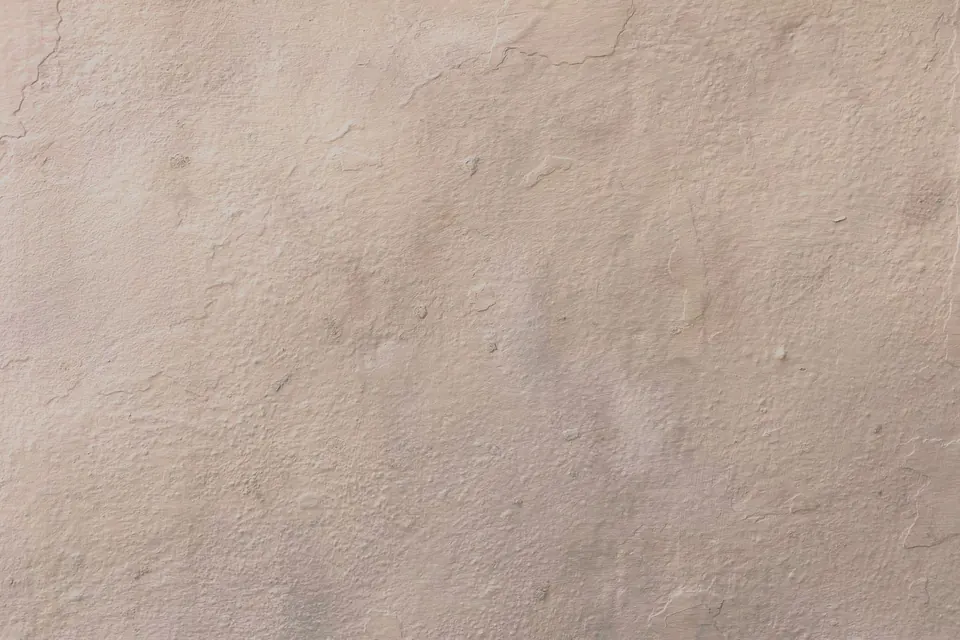Gladde, beige gestuukte muur met een zacht lichtverloop