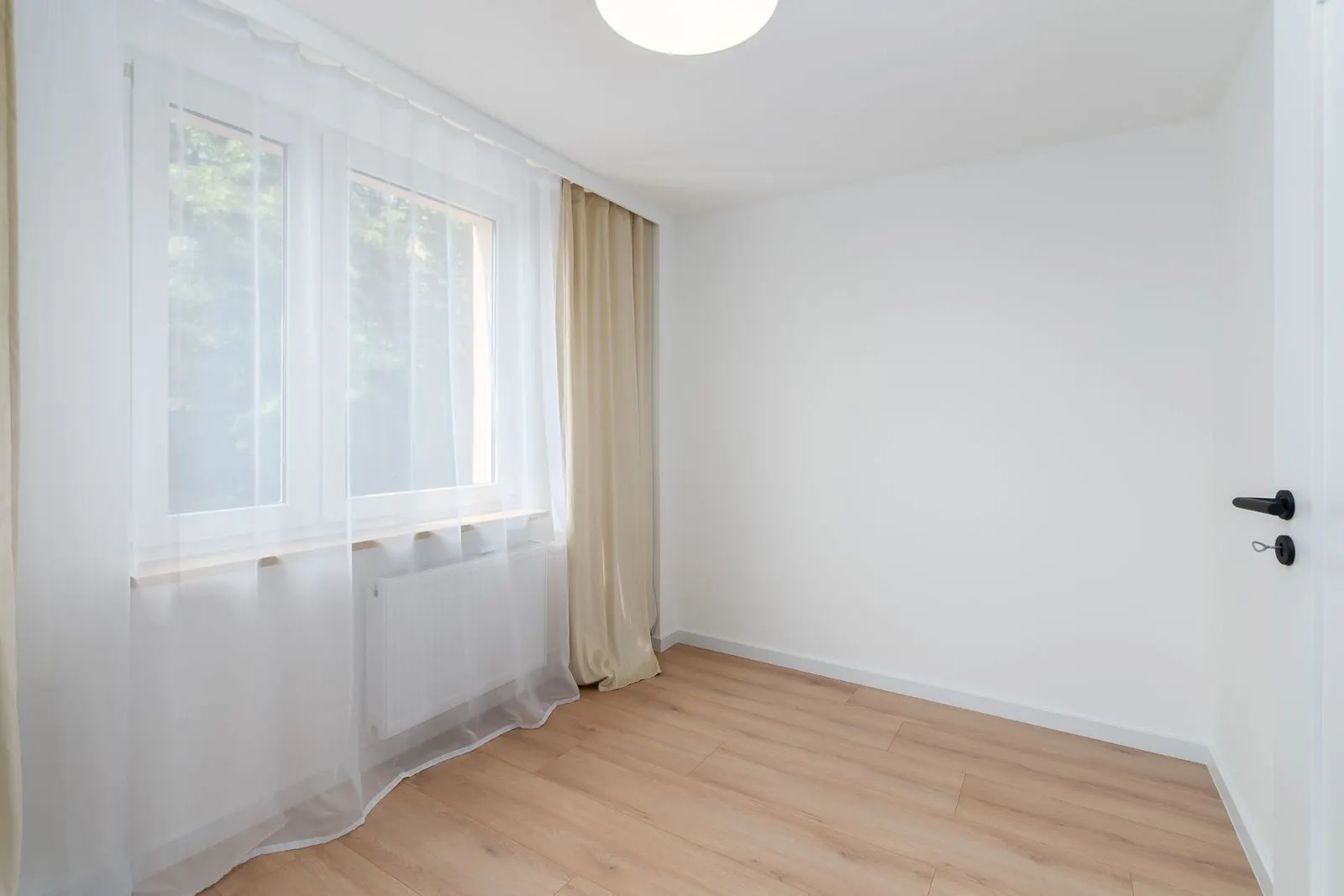 Na: lichte kamer met gladde witte muren en een raam met vitrage