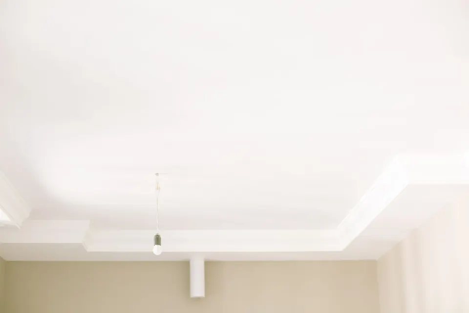 Wit plafond met een lijst langs de rand en een hangende lamp