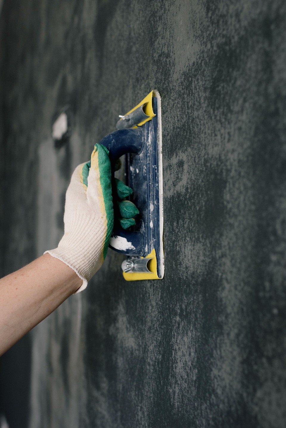 Een hand met een groene handschoen houdt een float tegen een donkere wand